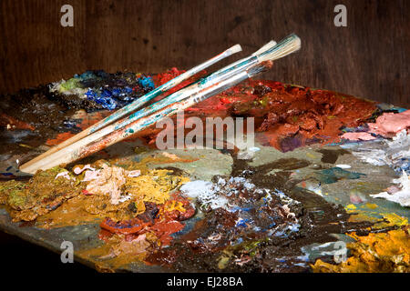 Painter's brushes and pallet full of colorful paint Stock Photo