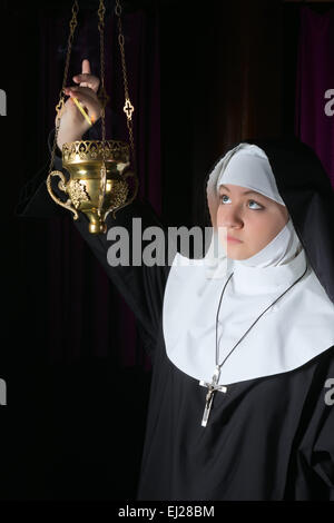 Nun in habit burning incense in a copper burner Stock Photo