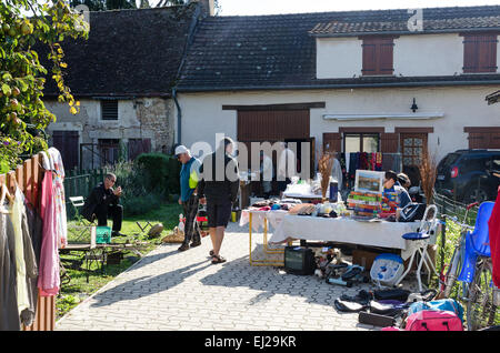 A family sets up tables in their driveway for the August flea market in Gigny-sûr-Saône, France. Stock Photo