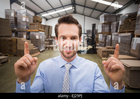 Smiling warehouse manager pointing up with finger Stock Photo