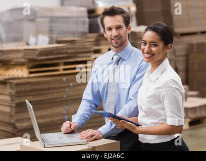 Managers working on laptop while smiling at camera Stock Photo