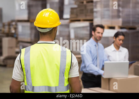 Rear view of warehouse worker in front of his managers Stock Photo