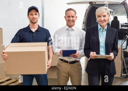 Warehouse managers and delivery driver smiling at camera Stock Photo