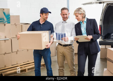 Delivery driver checking his list on tablet with managers Stock Photo