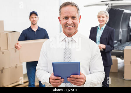 Smiling manager holding tablet in front of his colleagues Stock Photo