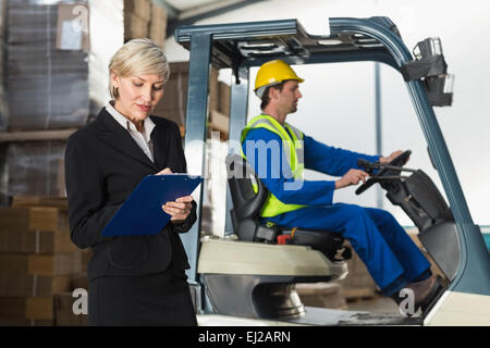 Manager writing on clipboard in front of her colleague Stock Photo