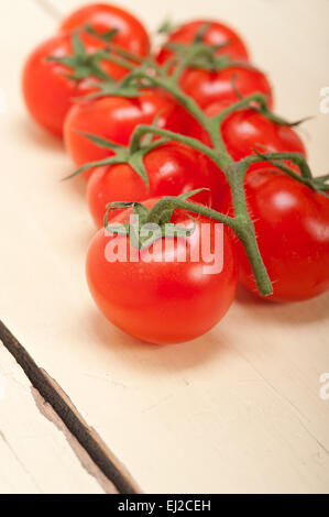 fresh cherry tomatoes on a cluster over rustic wood table Stock Photo