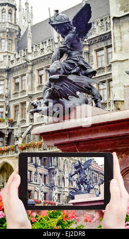 travel concept - tourist takes picture of sculpture on Mary's Column (Mariensaule) at marienplatz square in Munich on smartphone Stock Photo