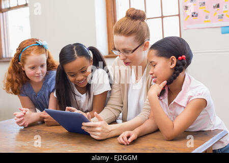 Teacher and pupils looking at tablet computer Stock Photo