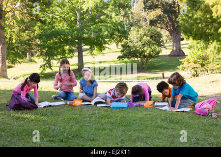 School children doing homework on grass Stock Photo