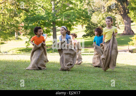 Children having a sack race in park Stock Photo