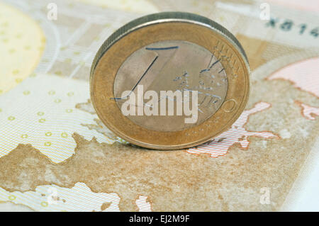 one euro coin standing on the map of a banknote Stock Photo