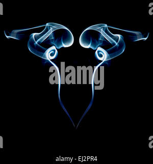 Abstract image of smoke curling upwards from an incense stick, reflected showing a mirrored pattern on a black background Stock Photo