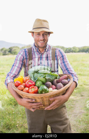 Cheerful organic farmer holding a box with fresh vegetables. Young ...