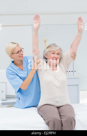 Nurse assisting female patient in exercising Stock Photo