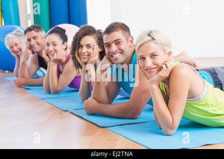People relaxing on exercise mats at fitness studio