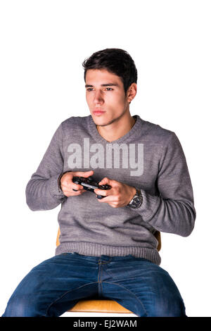 Attractive young man using joystick or joypad for videogames, isolated on white, sitting on stool Stock Photo