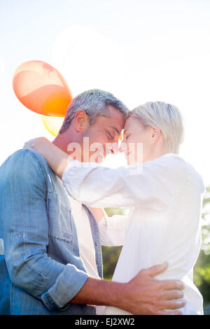 Cute couple hugging and holding balloons in the park Stock Photo - Alamy