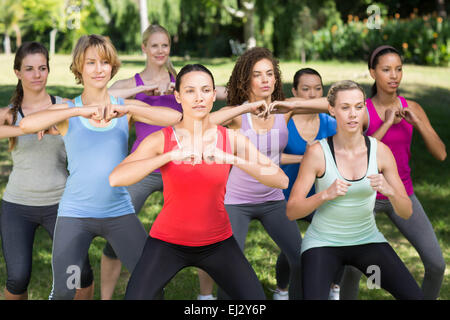 Fitness group squatting in park Stock Photo