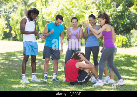 Fitness group encouraging man doing sit ups Stock Photo