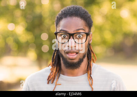 Handsome hipster looking surprised in park Stock Photo