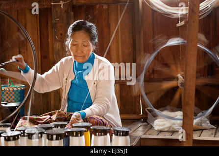 Senior burmese woman spinning silk yarn on a spinning wheel, In Paw Khone village, Inle Lake, Myanmar ( Burma ), Asia Stock Photo