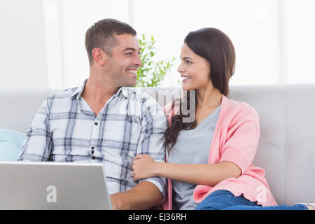 Couple looking at each other while using laptop Stock Photo