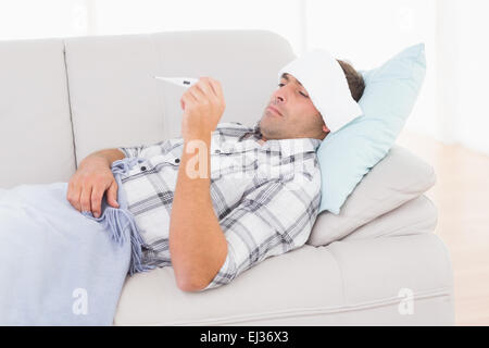 Ill man checking temperature on thermometer Stock Photo