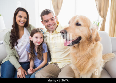 Family sitting with Golden Retriever on sofa Stock Photo