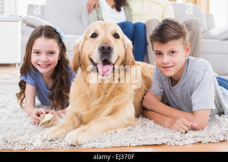 Siblings lying with dog while parents relaxing on sofa Stock Photo