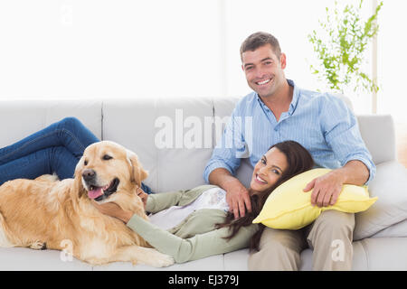 Happy couple with dog relaxing on sofa Stock Photo