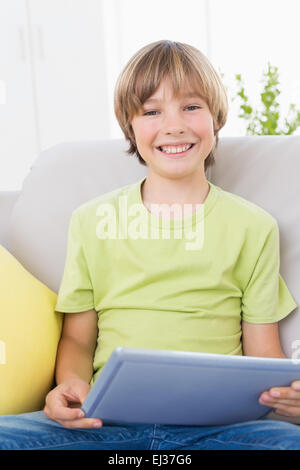 Happy boy using digital tablet on sofa Stock Photo