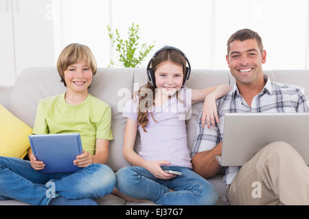 Happy man with children using technologies on sofa Stock Photo