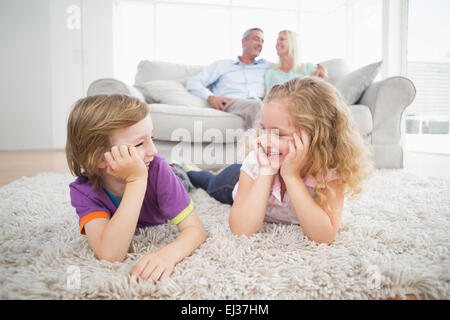 Siblings looking at each other while parents sitting on sofa Stock Photo