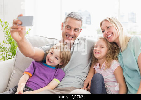 Man taking selfie with family on sofa Stock Photo