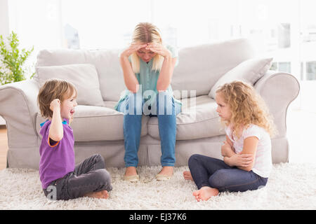 Upset woman sitting on sofa while brother teasing sister Stock Photo