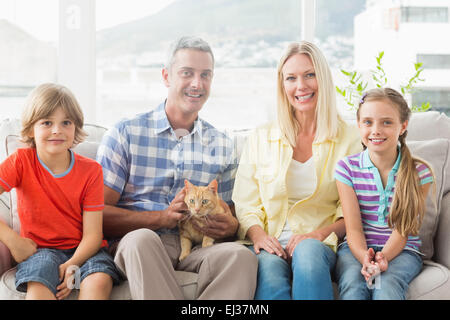 Portrait of happy family sitting with cat on sofa Stock Photo