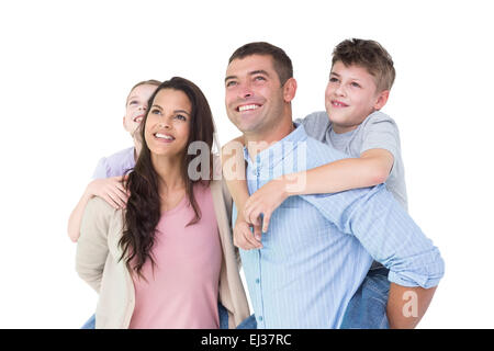 Happy parents giving piggyback ride to children while looking up Stock Photo