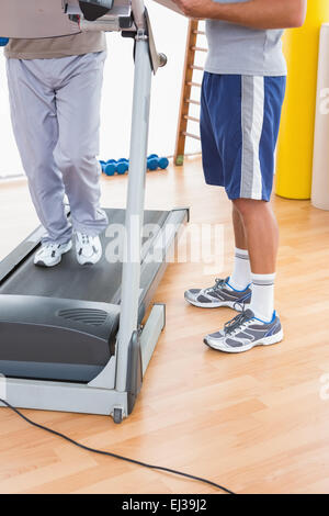 Senior man on treadmill with trainer Stock Photo
