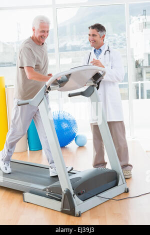 Senior man on treadmill with therapist Stock Photo