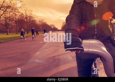 closeup of a young caucasian man very sheltered riding a bicycle in Hyde Park in winter in London, United Kingdom, filtered and Stock Photo