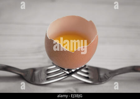 Broken egg rests on two forks Stock Photo