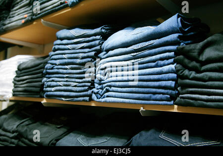 Many folded jeans on shelves in a shop Stock Photo