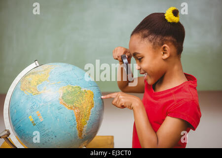 Little girl looking at globe through magnifying glass Stock Photo