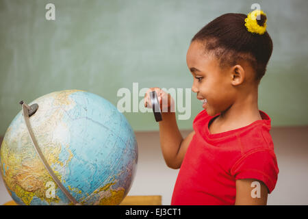 Girl looking at globe through magnifying glass Stock Photo