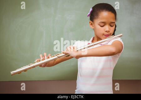 Little girl playing flute in classroom Stock Photo