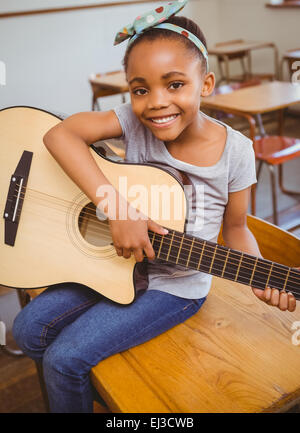 Little girl playing guitar in classroom Stock Photo