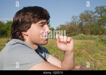 Young man sitting in a meadow on a sunny day Stock Photo