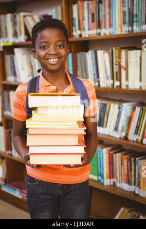 Cute little boy carrying books in library Stock Photo