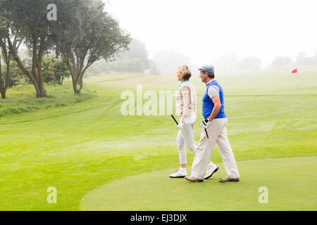Golfing couple walking on the putting green Stock Photo